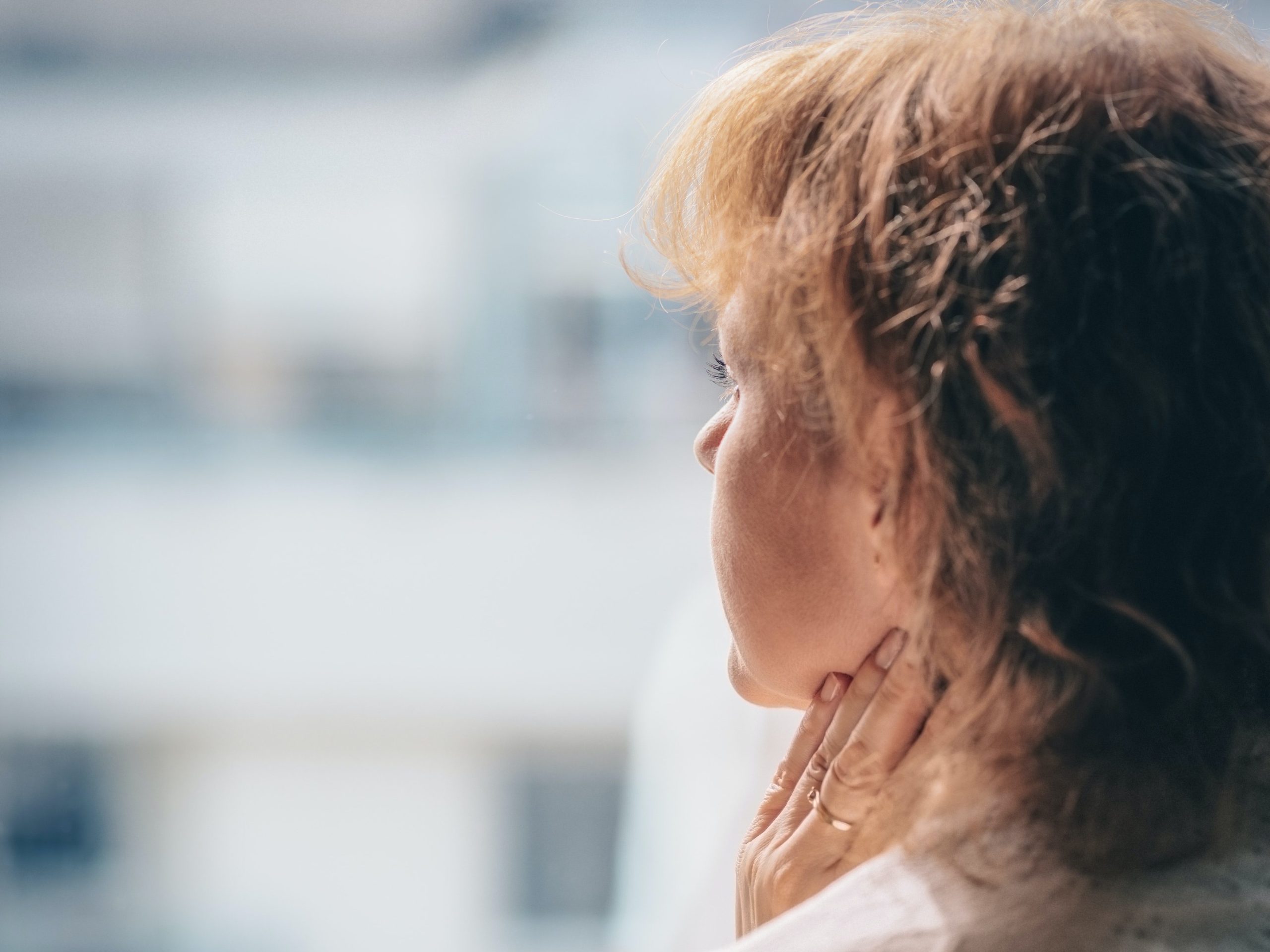 Woman staring into the distance with fingers on her neck