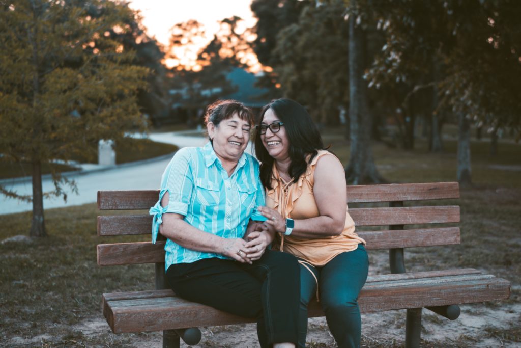 Woman and her mother on a bench in the middle of a park.